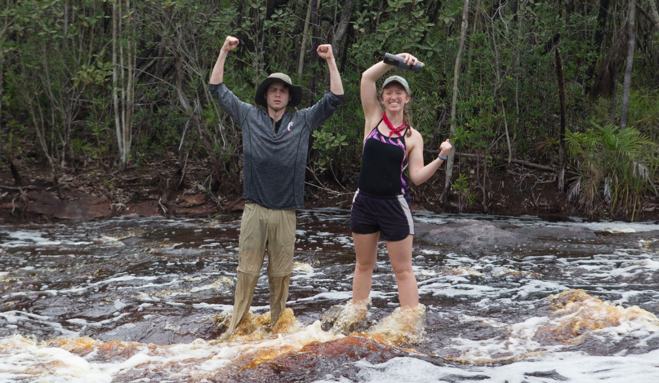 Students signing U-C in a running stream.