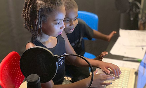 Young children work together on a laptop