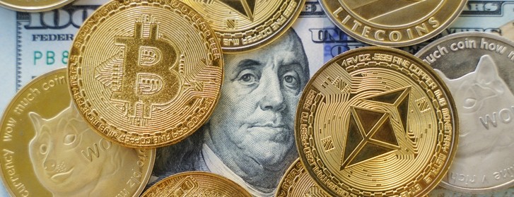 Close up shot of Bitcoin and other cryptocurrency coins on a $100 bill.
