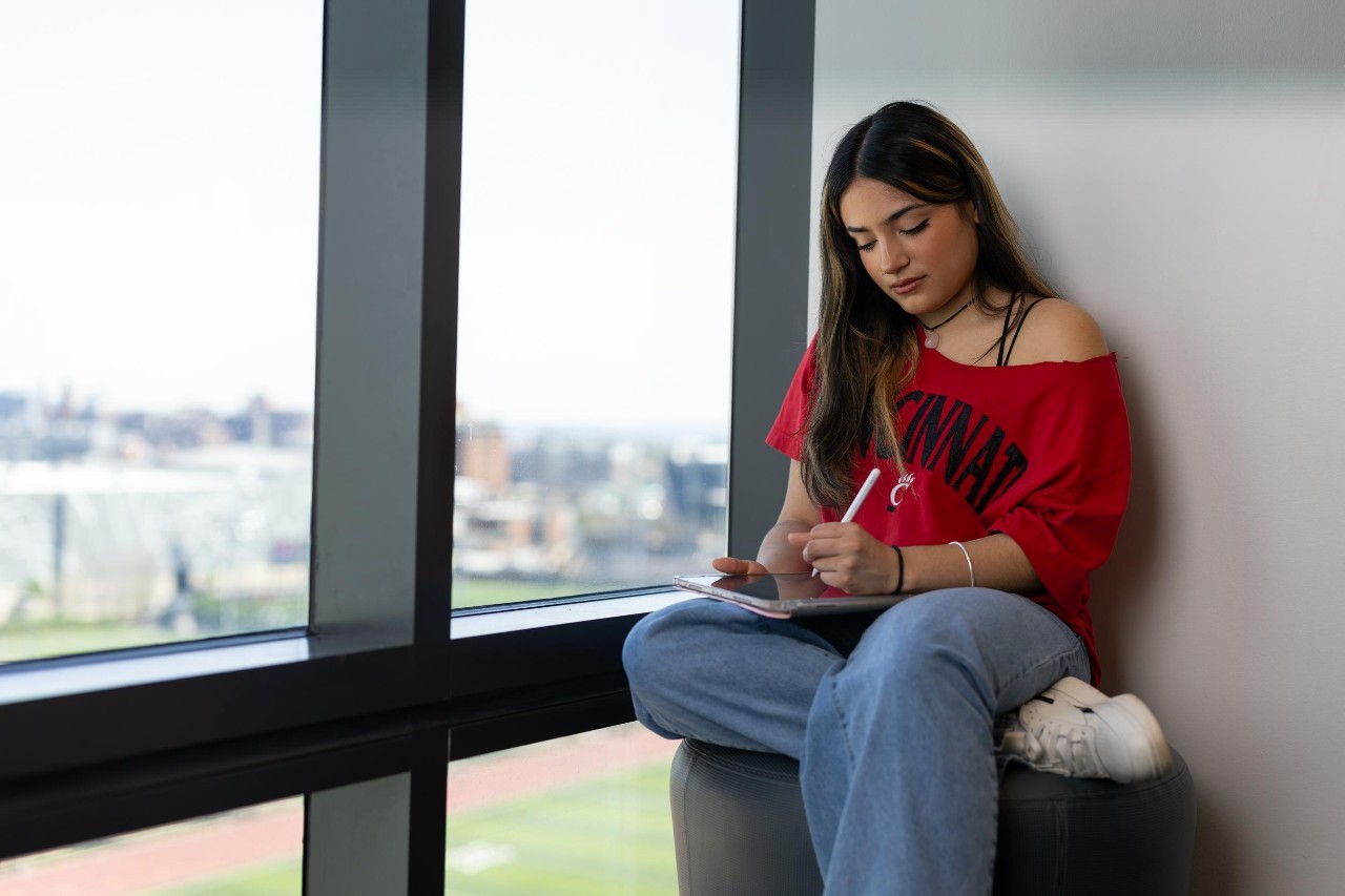 Independent FAFSA student writing by a window on her iPad