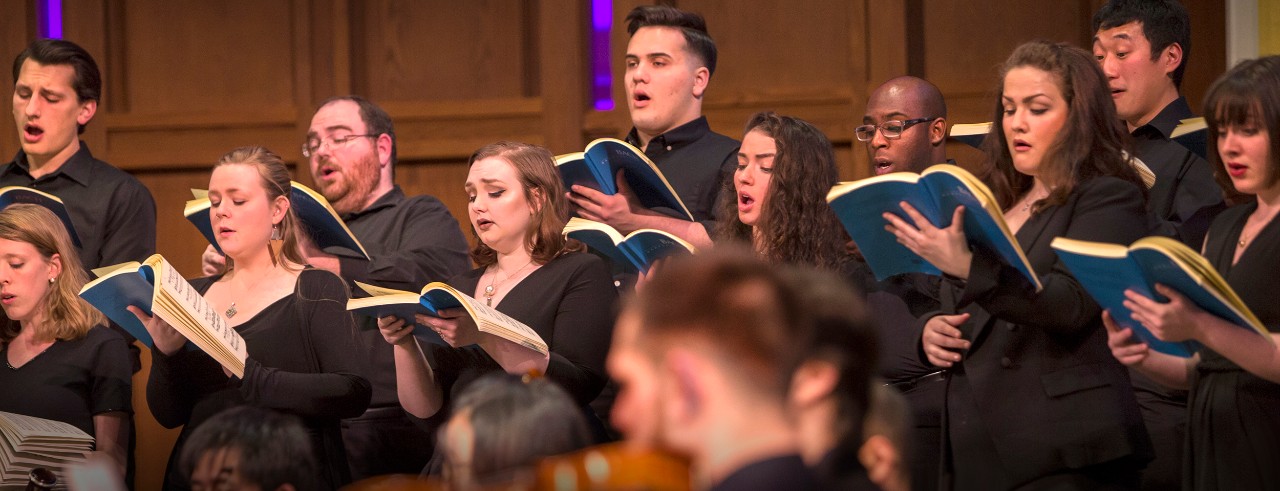 CCM orchestra and choirs perform on stage.